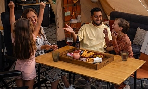 familie in de tent gezellig aan tafel Gezin geniet van een maaltijd met frietjes en dips in een gezellige tent met houten tafel